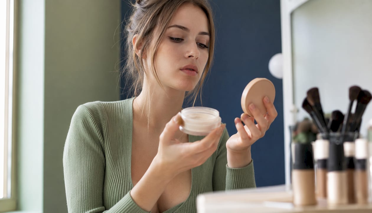 Μια γυναίκα εξετάζει και συγκρίνει τις πούδρες σε compact μορφή με τις ελεύθερες, προσπαθώντας να δει ποια ταιριάζει καλύτερα στις ανάγκες της και στο δικό της τύπο δέρματος.